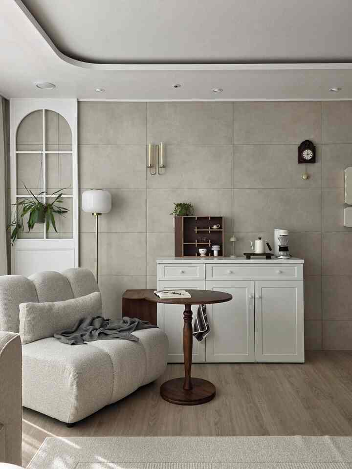 ナチュラルな木目調と明るいトーンの収納キャビネットが配置されたミニマルなリビング、柔らかいソファと丸いサイドテーブルが調和する印象的な空間