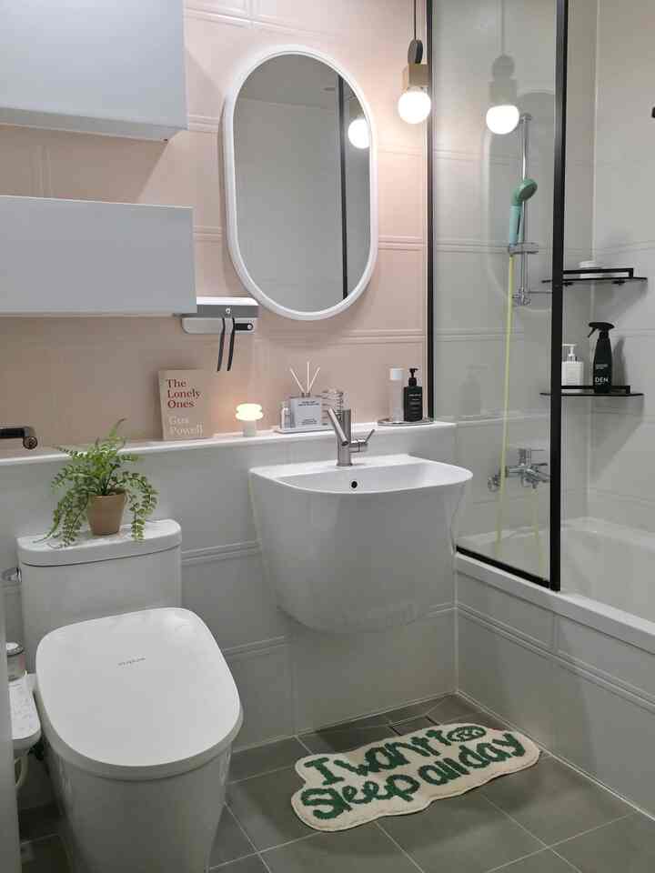 清潔感のあるホワイトにグリーンアクセントが映えるモダンなバスルーム、トイレと洗面台、浴槽が調和した印象的な空間