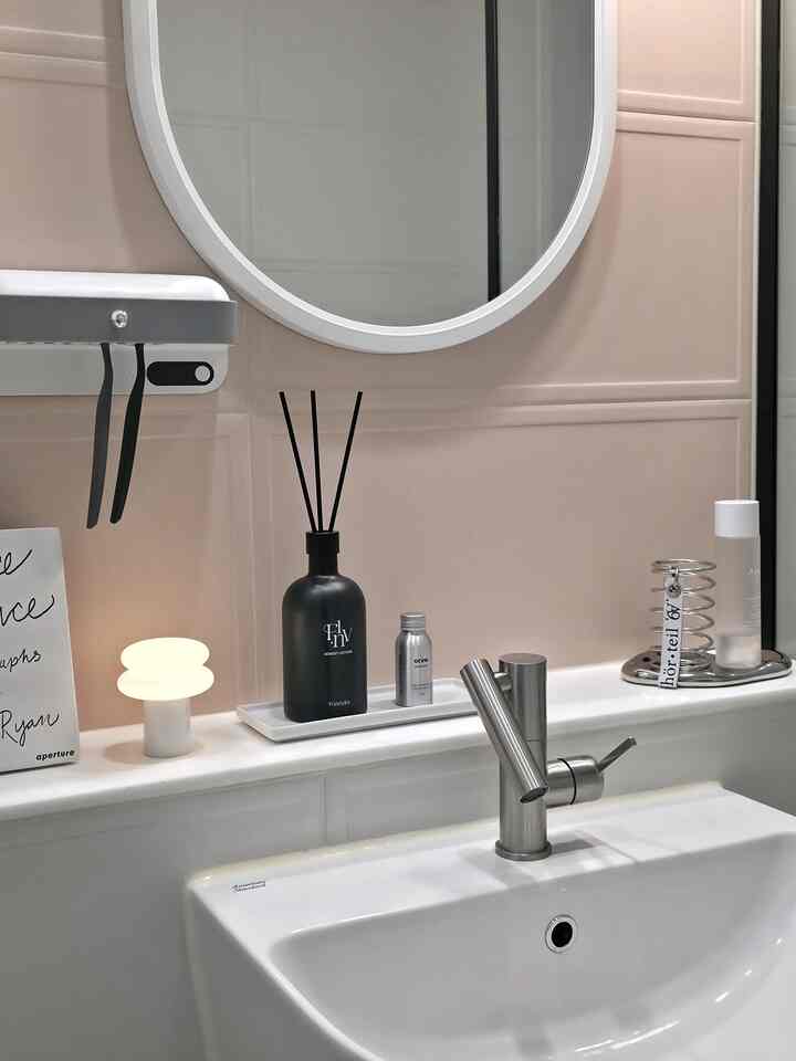 白とベージュの色調のバスルーム、洗面台とディフューザーが配置された清潔感のある空間