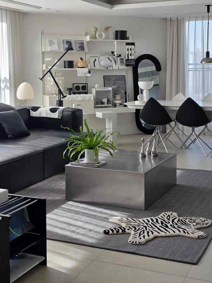 Monotone modern living room featuring black sofa, metallic coffee table, and white dining table with chairs in a harmonious space