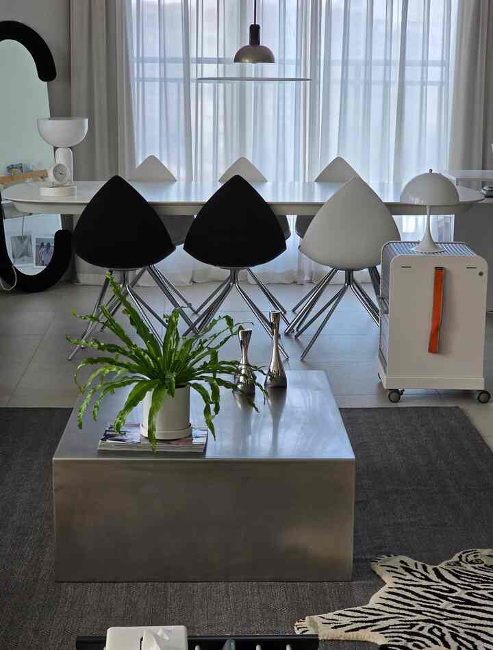 Modern dining room in white and black tones featuring triangular chairs and a long dining table with a clean aesthetic