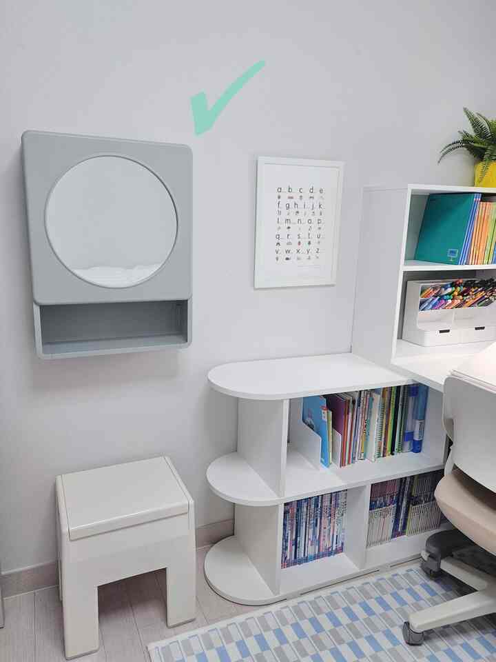 白を基調とした子供部屋、本棚、机、スツール、壁掛け鏡が配置された清潔で子どもに優しい雰囲気のインテリア