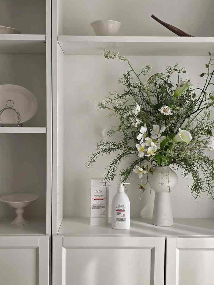 白を基調とした書斎、白いセラミックの花瓶に豊かな造花が配置されたシンプルで自然な雰囲気のインテリア