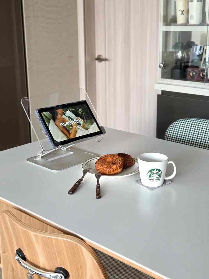 ナチュラルな色調のダイニングルーム、ホワイトのテーブルに皿とコーヒーカップ、タブレットが配置された清潔感のある空間