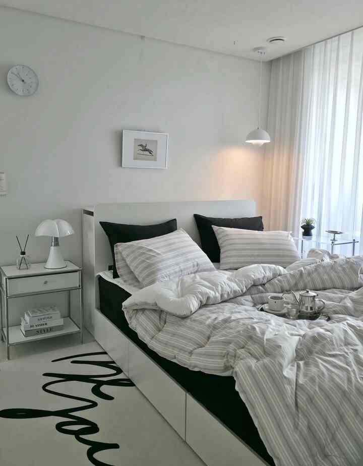 ホワイトとブラックのモダンな寝室、ホワイトベッドとストライプ柄の寝具が配置された雰囲気のある空間