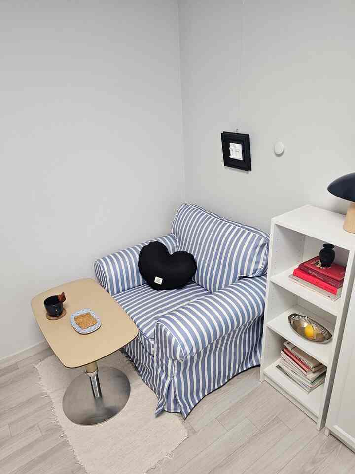 White and beige corner space featuring striped armchair and small table with cozy atmosphere