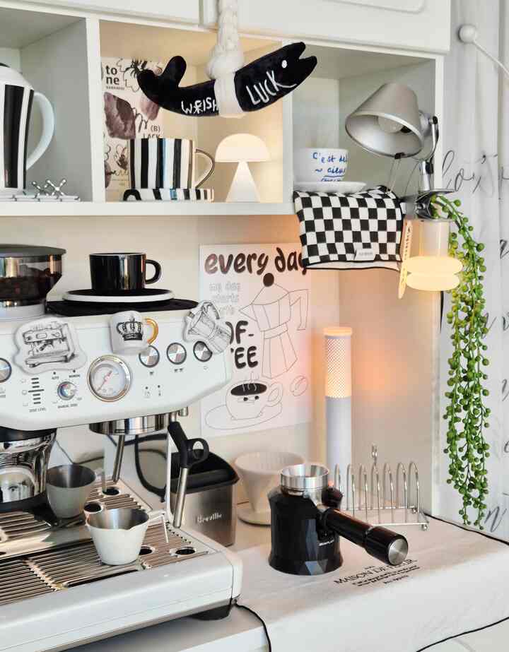 白と黒のトーンのホームカフェ空間、コーヒーマシンとカップ、照明が配置された雰囲気のあるインテリア
