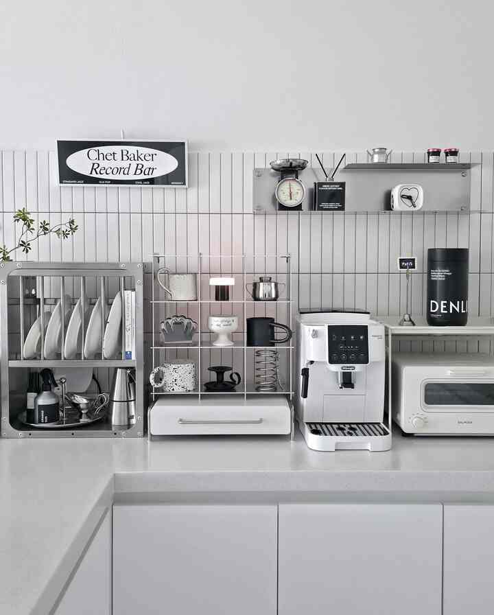 ホワイトとグレーの色調のキッチン、コーヒーマシンとステンレスの棚が整然と配置されたモダンなおうちカフェのインテリア