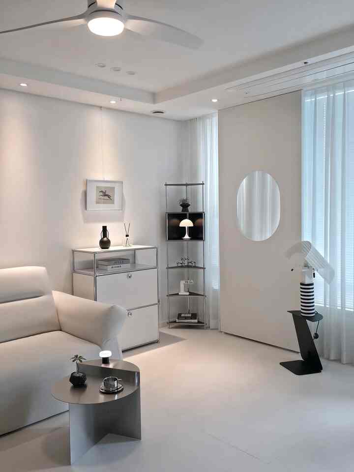 白と黒のモノトーン調のリビング、ミッドセンチュリーモダン家具とコーナー収納、モダンな照明が配置された印象的な空間