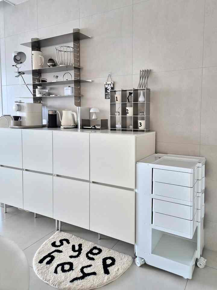 White and gray toned living room home cafe featuring minimal and modern storage cabinets and metal shelving with a clean interior