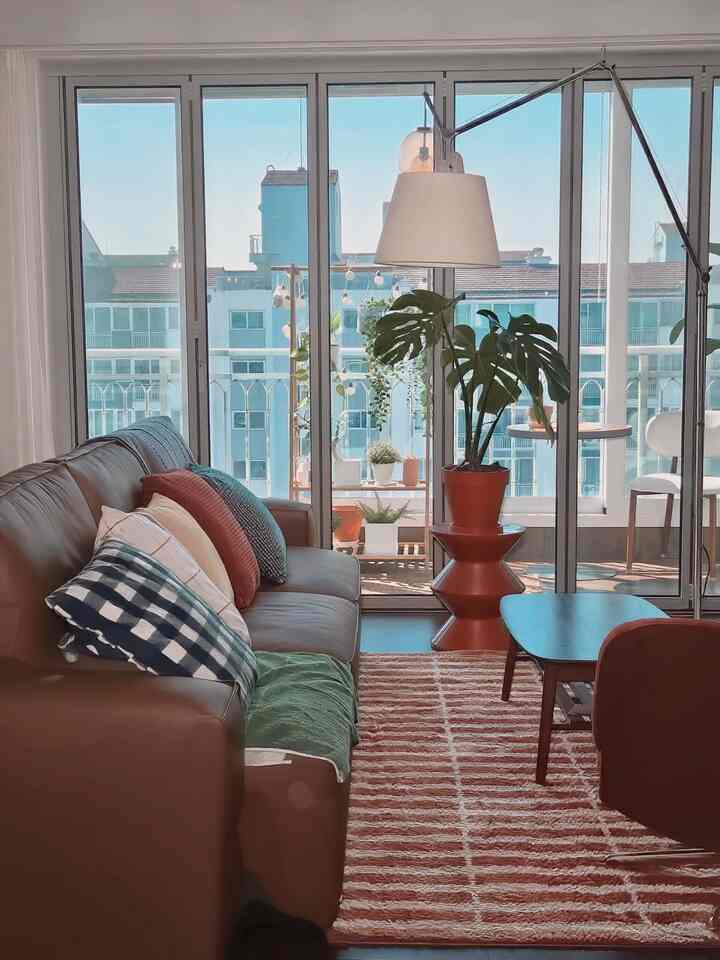 暖かいベージュとブラウンの色調のリビング、レザーソファとオレンジのラグがくつろぎの空間を演出