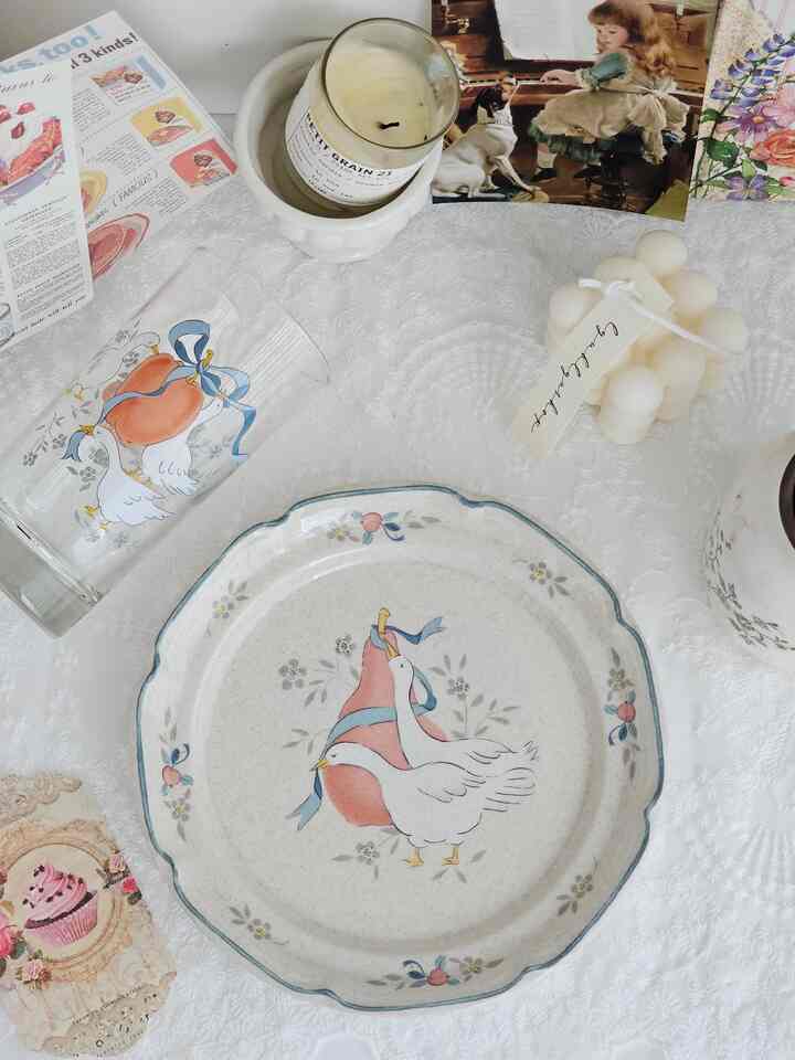 白いレースのテーブルランナーの上にフレンチカントリー風の飾り皿やキャンドル、オブジェが置かれた雰囲気のあるテーブルセッティング