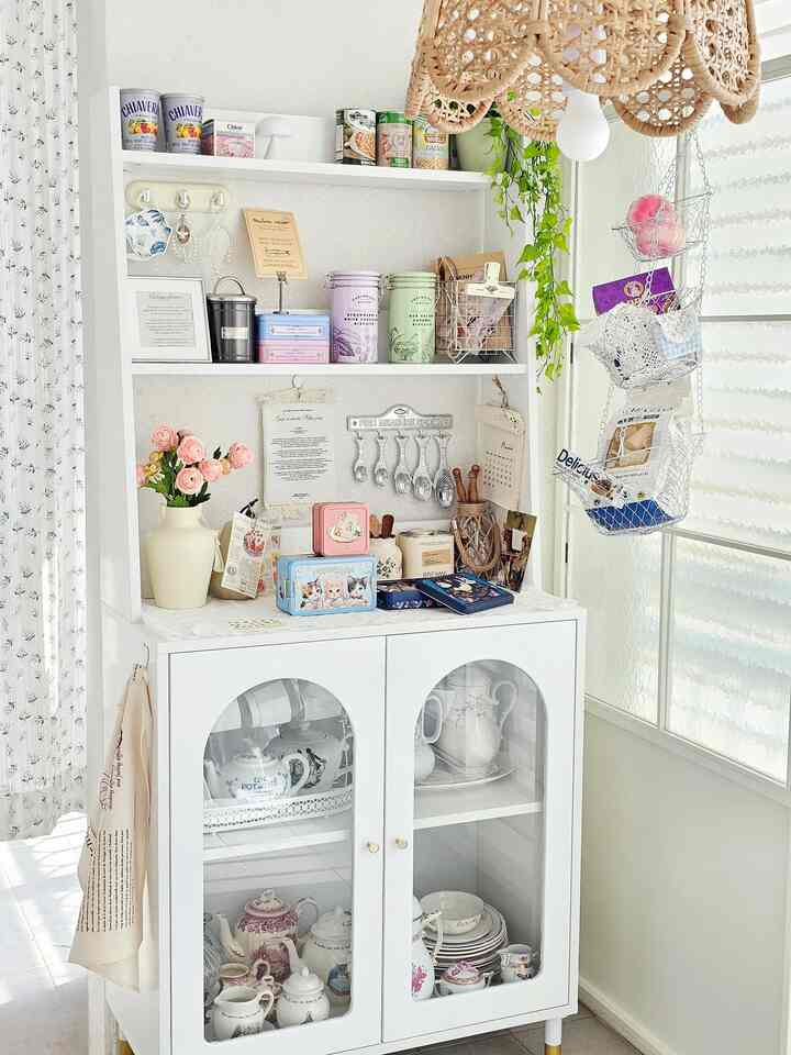 白とベージュの色調のキッチンコーナー、花瓶と植物の装飾が配置された雰囲気のある収納キャビネット