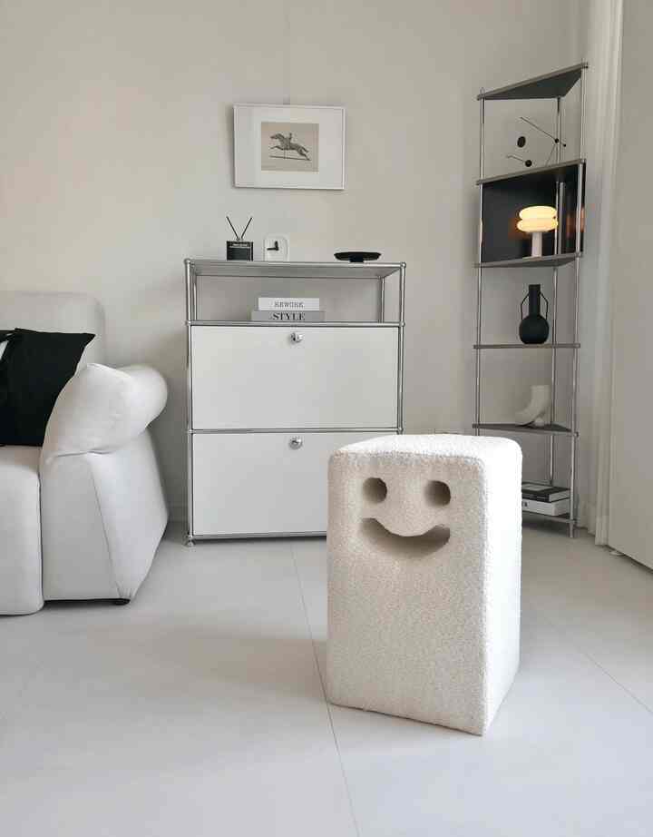 白とミッドセンチュリーモダンのリビング、スマイル形のスツールとナイトテーブル、金属製の棚が配置されたミニマルな雰囲気のインテリア