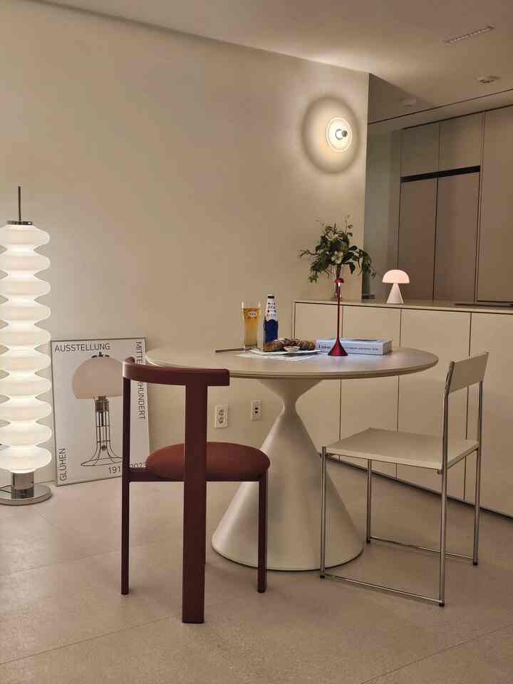 Beige-toned dining room with modern table and chairs, featuring various lighting fixtures creating a cozy atmosphere