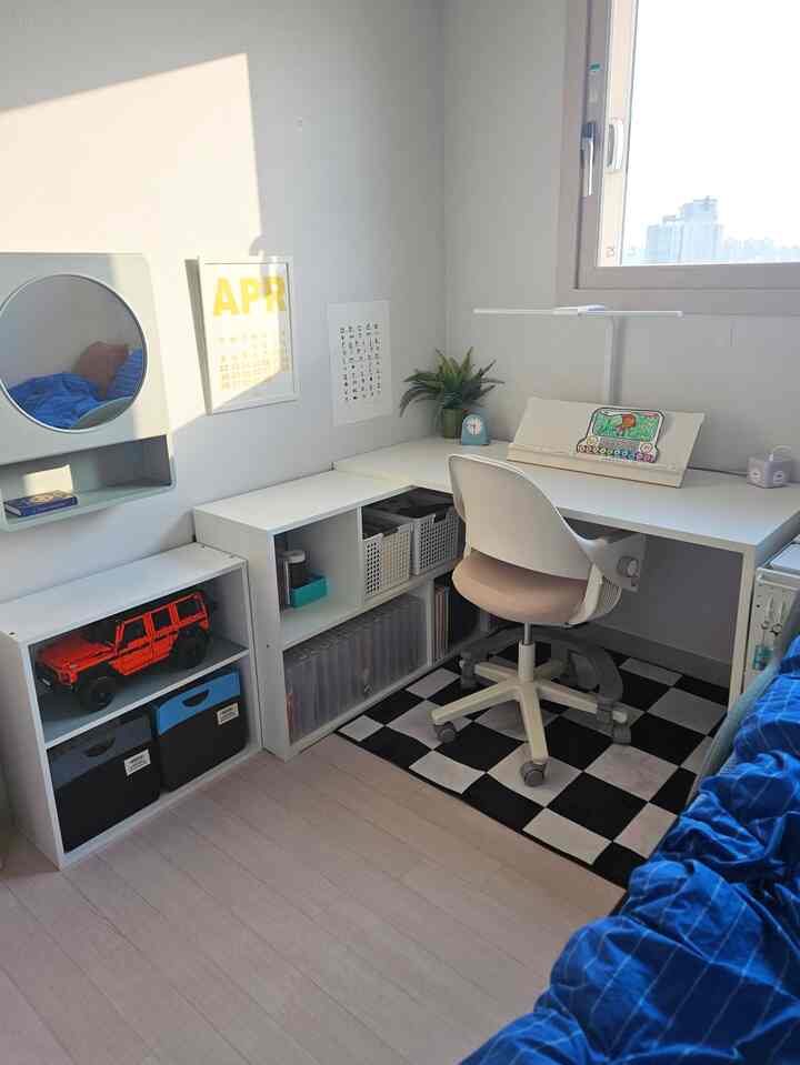 白と青の色調の子供部屋、コーナーデスクと収納棚が配置された整った雰囲気のある学習スペース