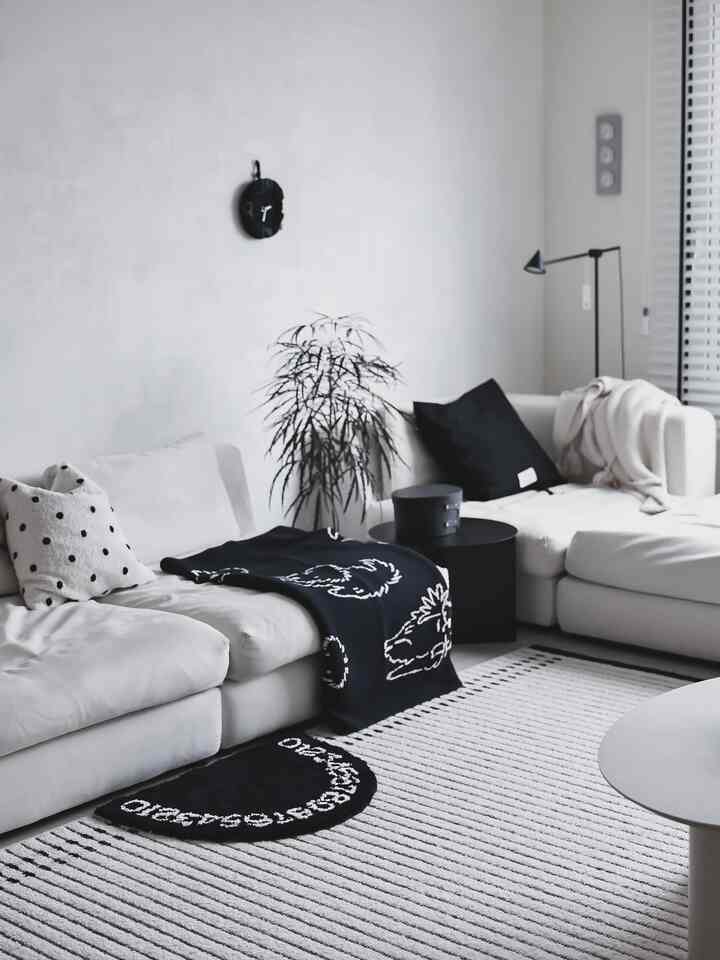 White-toned living room featuring a modern white sectional sofa with black accent cushions and throw, creating a clean space