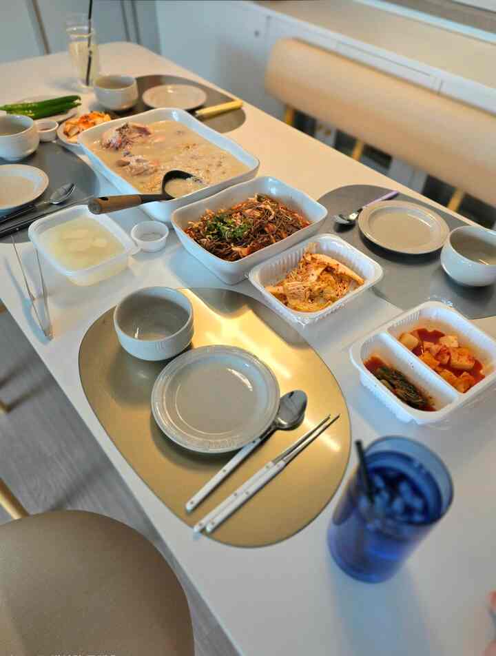 柔らかなベージュ調のダイニングテーブルに伝統的な韓国料理と器、カトラリーが整然と配置された自然な雰囲気のインテリア