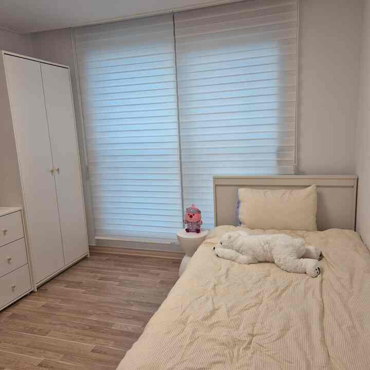 クリームベージュの子供部屋寝室、ベッドと白い家具が配置された居心地の良い空間