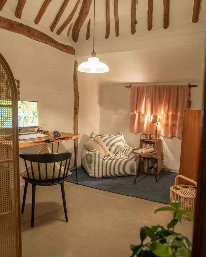 ナチュラルな木目調とホワイトの書斎空間、ストライプ柄のビーズクッションと木製デスク、ペンダントライトが温かみのある雰囲気を演出