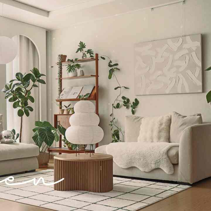 白と木目調のナチュラルなリビングルーム、ファブリックソファと木製コーヒーテーブル、多彩な植物が置かれた雰囲気のあるインテリア