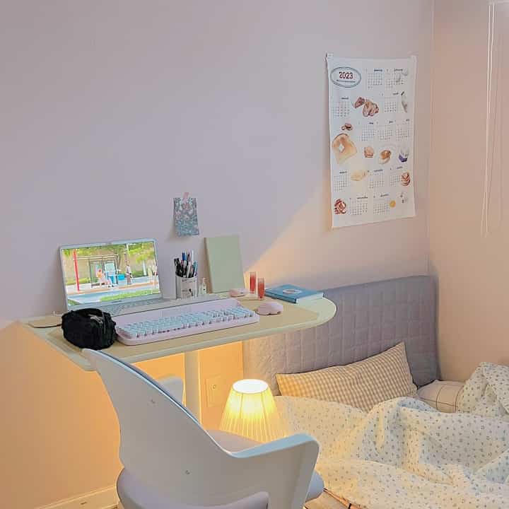 パステル調の色合いが特徴的なワンルーム、机と寝具が調和したミニマルで落ち着いたインテリア
