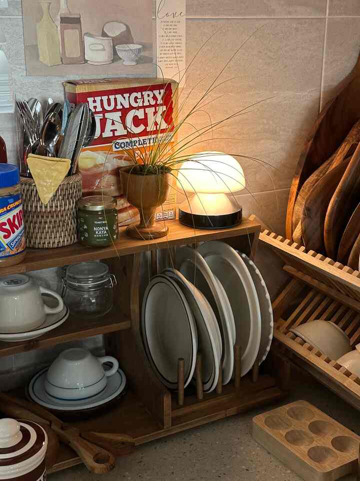 ナチュラルな木目調のキッチン、皿とボウルの収納アイデアとキノコ型のテーブルランプが置かれた雰囲気のあるインテリア