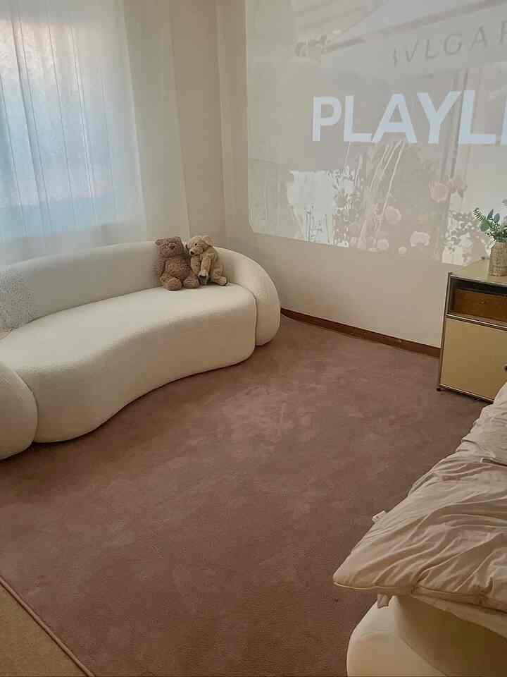 ベージュとホワイトの色調の寝室、曲線ソファとテディベアが置かれたシンプルでナチュラルな雰囲気のインテリア