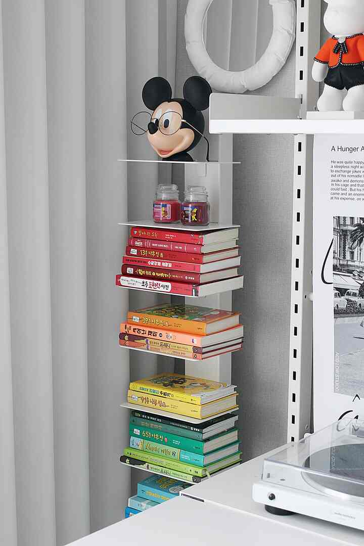 White-toned small shelf corner featuring neatly stacked colorful children's books with a modern feel