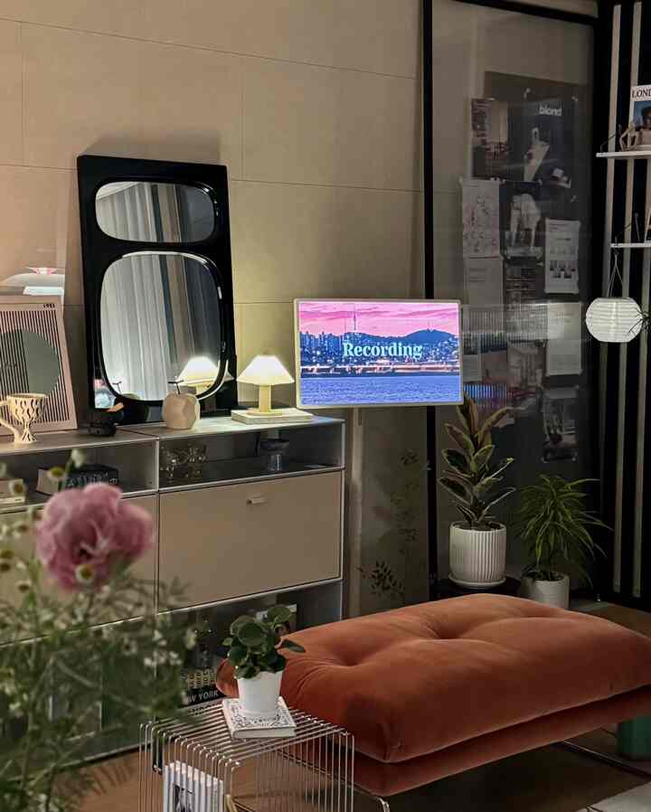 Natural-toned living room featuring a brown bench, plants, large mirror, and a TV stand in a cozy setting