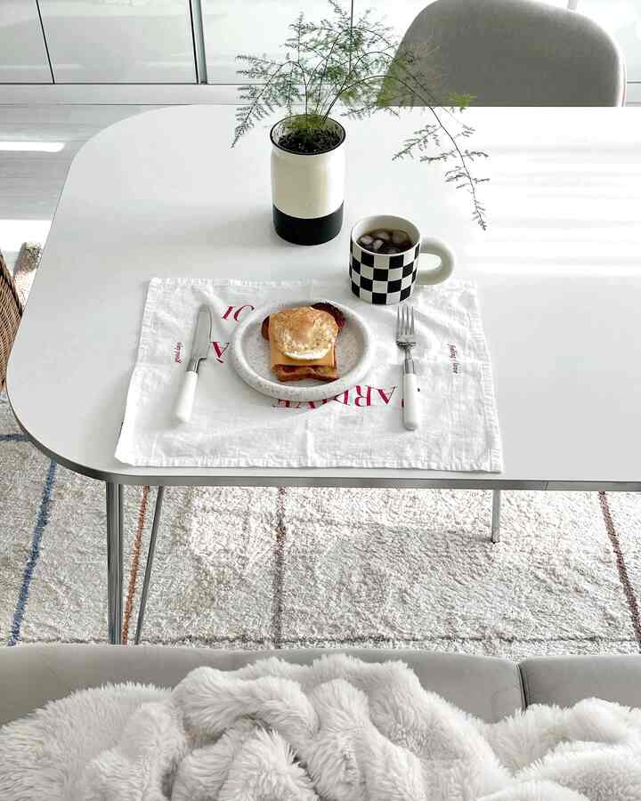 White dominant dining room featuring a black-and-white checkered mug and breakfast setup on a clean, cozy table