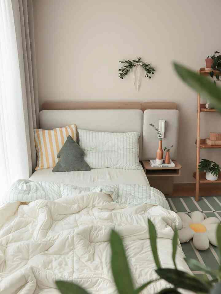 温かみのあるアイボリー色調の子供部屋、木製のベッドフレームと多様な植物が配置された自然な空間