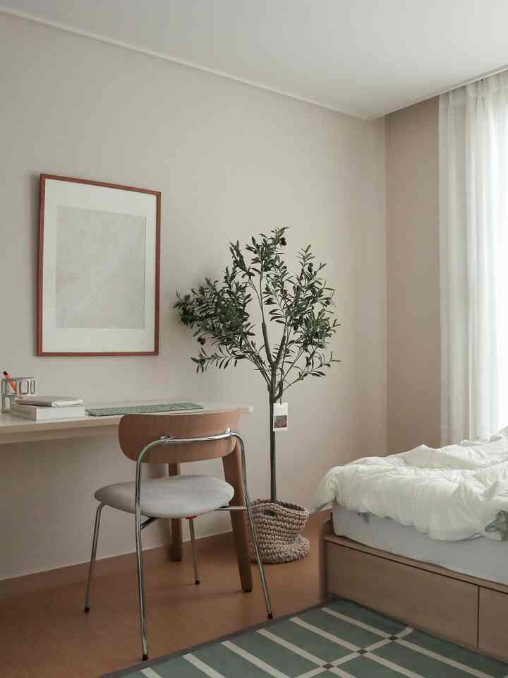 ベージュ色調の子供部屋、木製のベッドとデスク、植物が配置された落ち着いたナチュラルな雰囲気のインテリア