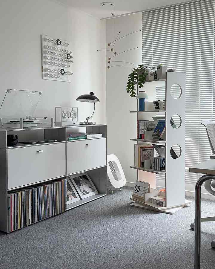白とグレー調のモダンな書斎、回転式本棚とアルミブラインド、ターンテーブルが配置された洗練された空間