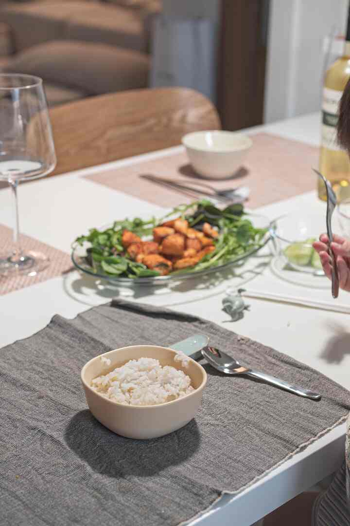 ベージュとホワイトの色調が特徴のキッチンのダイニングテーブル、米の入ったボウルと透明な食器が配置された雰囲気のある空間