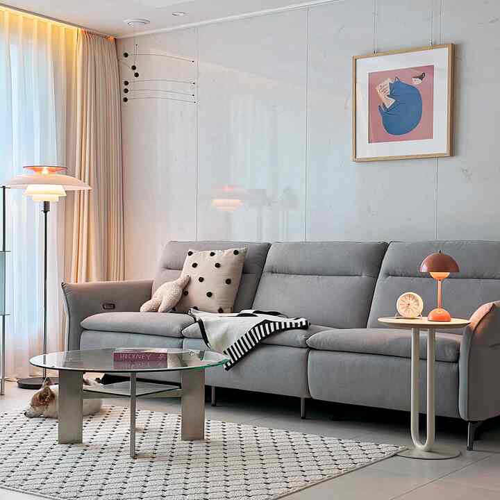 グレーのソファとベージュのカーテン、ガラステーブルが配置されたナチュラルモダンなリビングルーム