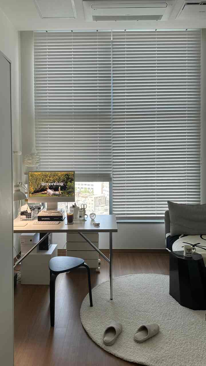 ホワイトトーンのワンルームホームオフィス、デスクとホワイトブラインドが配置された清潔感あるモダンなインテリア