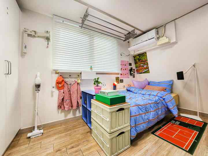 White and natural tones blend in this studio bedroom featuring white wood blinds at the window and efficient storage boxes for a cozy atmosphere