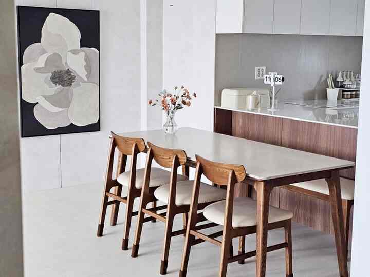 White and brown toned kitchen and dining area featuring a wooden dining table and framed art, modern and natural interior