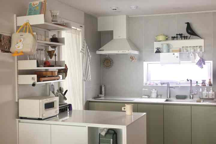 白とライトグレーのトーンのキッチン、壁棚と整頓されたキッチン用品が配置された清潔感のある空間