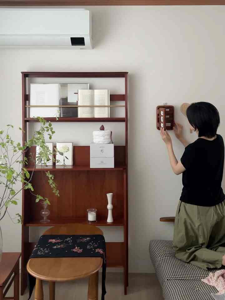 木目調の寝室、マルチキャビネットと丸いサイドテーブル、さまざまなインテリア小物が配置された雰囲気のある空間