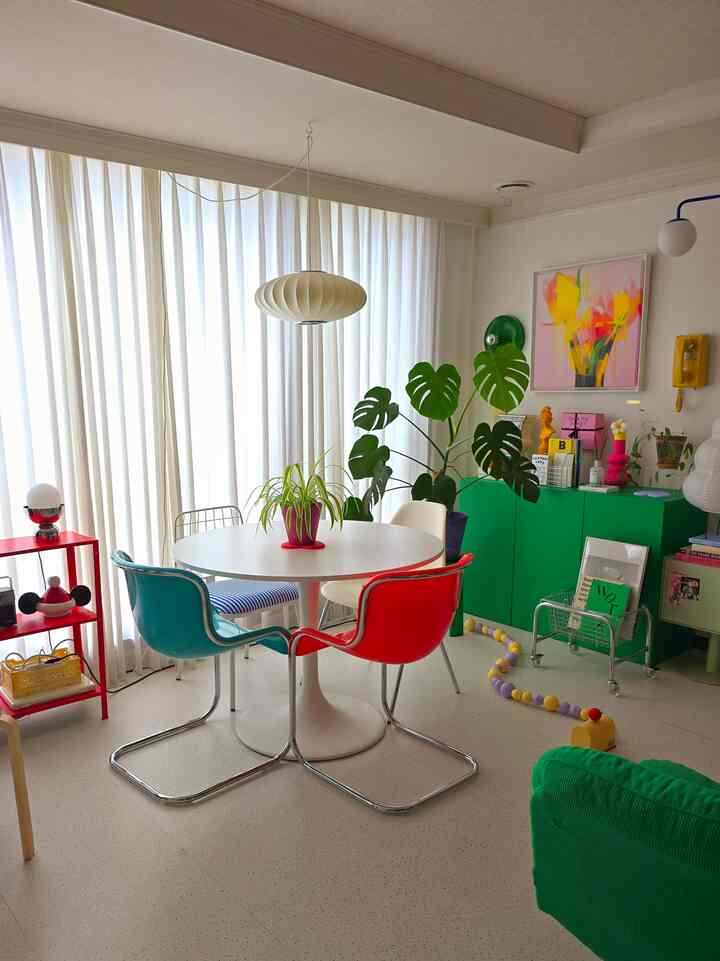 ホワイトとグリーンの色調のリビング、カラフルなダイニングテーブルとレトロな家具が配置された印象的な空間
