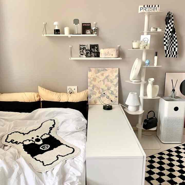 ナチュラルなベージュの壁と白いベッド、低い収納棚と棚が配置された落ち着いた寝室のインテリア