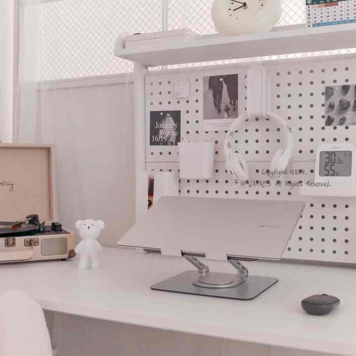 Bright white tone home office study space featuring a clean desk with pegboard and laptop stand for a simple aesthetic