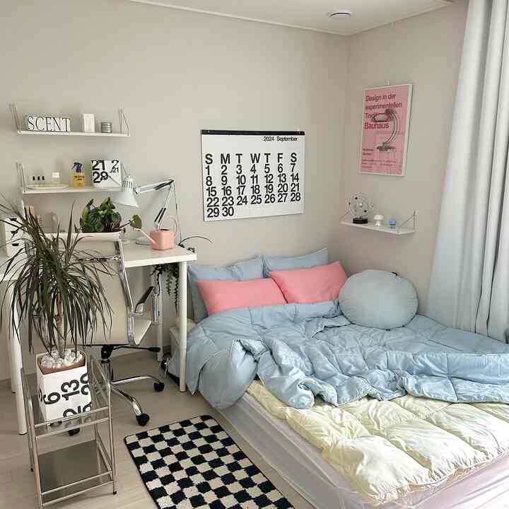 ホワイトの壁と家具が調和したモダンな一人暮らしの寝室、パステルブルーの寝具とピンクのクッションがアクセントの空間