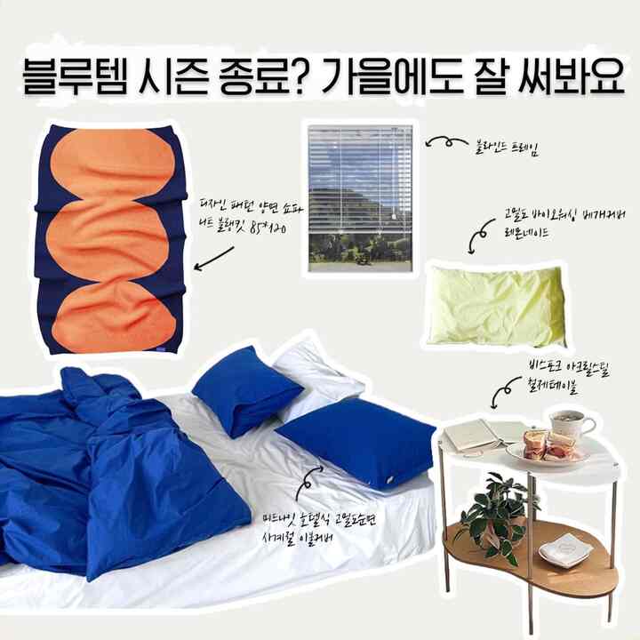 A cozy autumn bedroom blending blue bedding with an orange knit throw and wooden side table, creating a clean, stylish atmosphere