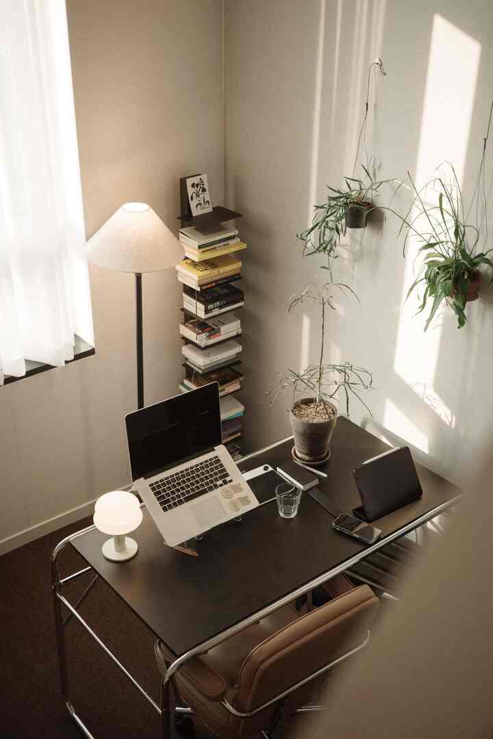 温かみのあるベージュと黒のトーンのホームオフィス、デスクにはノートパソコンと植物が配置された落ち着いた作業空間