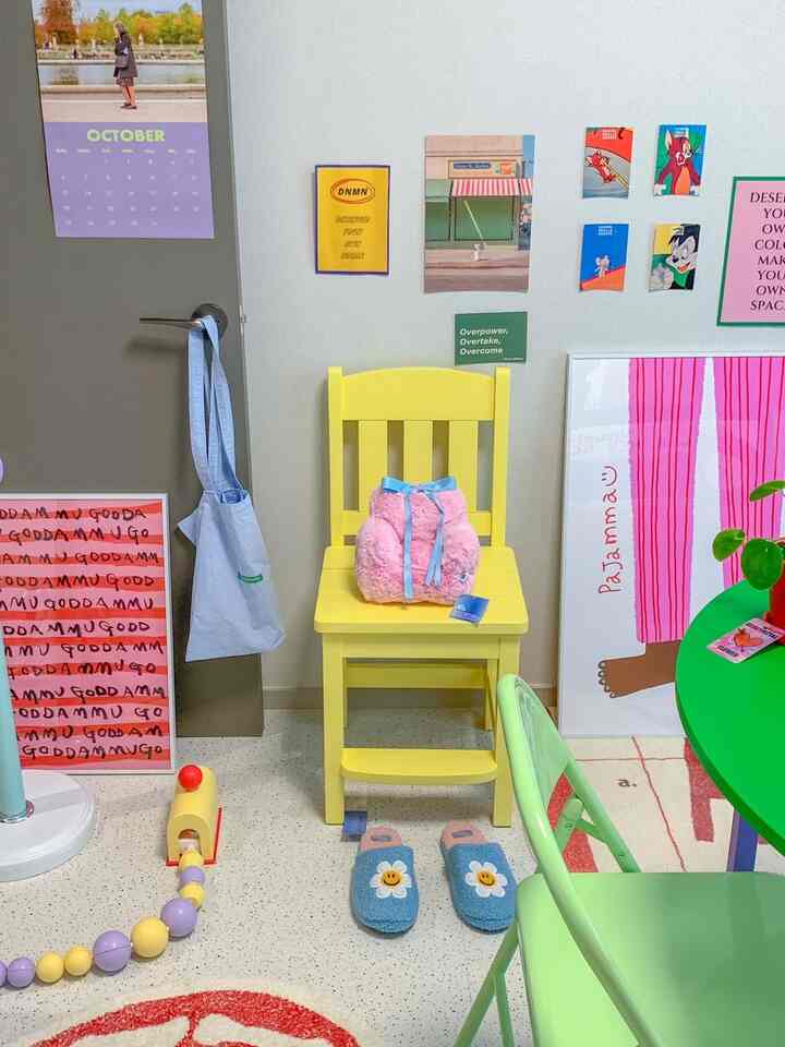 黄色い椅子とカラフルなポスターが並ぶ、子供用スリッパとおもちゃが置かれた温かみのある狭い部屋のインテリア
