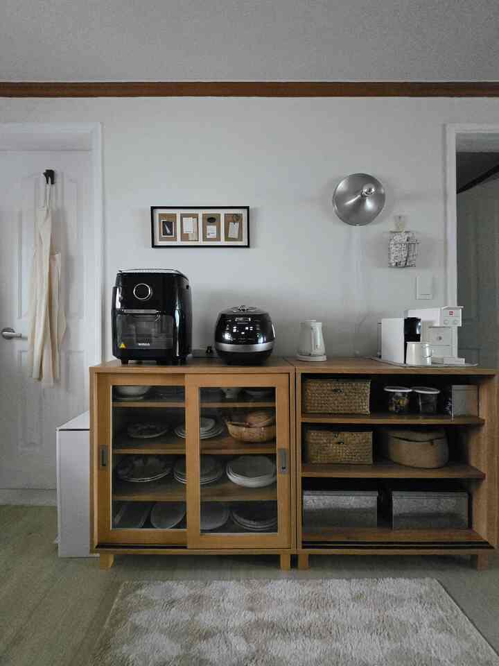 ナチュラルなウッド調とベージュ色のキッチン空間、コーヒーマシンと収納キャビネットが整然と配置された雰囲気のあるおうちカフェ