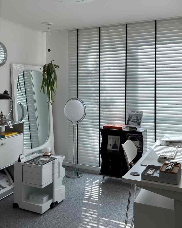 A compact home office space in white and black tones featuring a desk and storage units with clean design